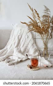 Tasse Tee und weißer Pullover auf dem Bett. Gemütliches Herbst- oder Winterkonzept.