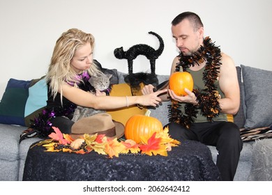 atraktívny muž a mladá žena vyrezávajú tekvice na halloween. oslavy amerických sviatkov na Slovensku. chlapec a dievča krájajú zeleninu so svojou britskou mačkou.