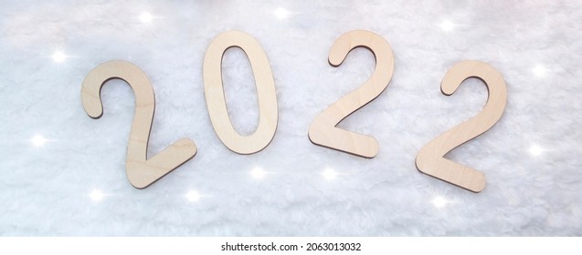 Happy New Year 2022. Number 2022 is made of wood on a wooden background. Christmas background with fir branches. ECO decorations. Banner