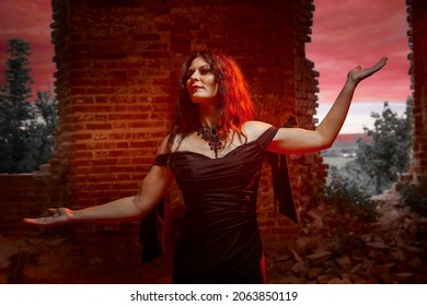 Cô gái Brunette với mái tóc dài trong chiếc váy dạ hội trong lâu đài Gothic cổ điển. Một người phụ nữ trông giống như một phù thủy độc ác hoặc phù thủy trong một nhà thờ cũ bị bỏ hoang. Người mẫu nữ tạo dáng trong Halloween