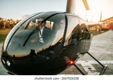 裕福な若いビジネス カップルは、自分のプライベート チョッパーやヘリコプターを使用して、職業やビジネス会議で旅行する準備をしています。