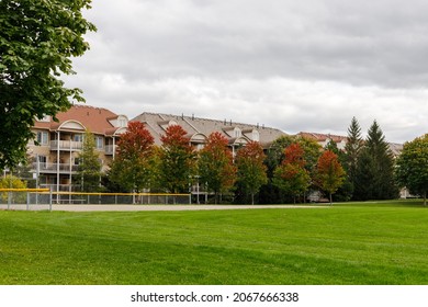 Residential house with apartments or condo building near park with baseball field in autumn season.