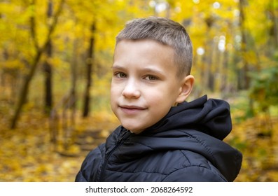 秋の黄色い森を背景に、ジャケットを着た笑顔の10歳の少年のポートレート。コンセプト: 秋の休日、もうすぐ学校に行く、森の中を歩く、旅行、娯楽。