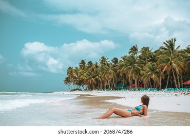 Meisje tot op het strand op zoek naar de kant. Geen gezicht. Mooie palmbomen en kust op de achtergrond. Zomer bewolkte dag in Dominicaanse Republiek.