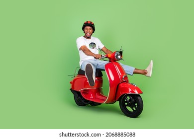 緑の色の背景に分離された若いアフリカ人ドライブ モーター バイク車両の全身プロファイル側の写真