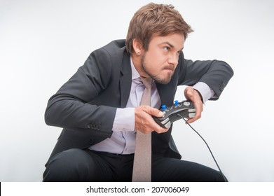 Sehr aufgeregter gutaussehender Geschäftsmann in perfektem schwarzen Anzug, der große Anstrengungen unternimmt, um ein Videospiel zu gewinnen