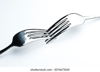 Two forks interwoven isolated on white background with subtle shadow