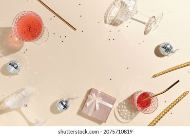 beige feestelijke achtergrond voor nieuwjaar of kerst met roze drankjes wijn, sap, punch, champagne en gouden confetti, discobal en geschenken met kopieerruimte