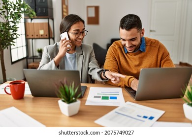 Two business workers talking on the smartphone and using laptop at the office.