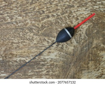 large black fishing bobber with red antenna long keel, still life