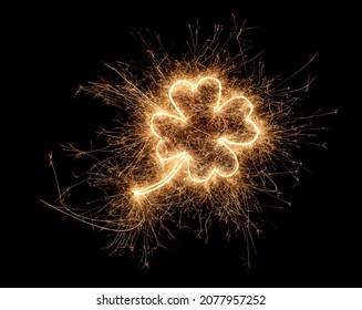 金色の明るい線香花火四つ葉のクローバーの形の幸せの形をしたシンボルは、暗い黒の背景に分離されました。シルベスター新年の誕生日の結婚式やお祝いのデザインパターン