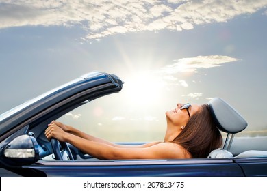 Portrait of Young girl driving cabriolet at sunset.