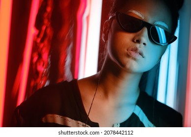 Chân dung cô gái trẻ châu Á đeo kính cận hình lưỡi liềm sành điệu với lông mày trắng, trong ánh sáng neon xanh đỏ. Khái niệm chân dung điện tử, tương lai
