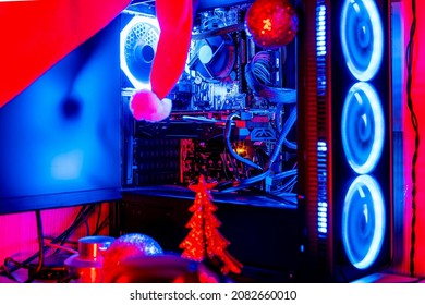 Computadora de escritorio con luces RGB junto a un pequeño árbol de Navidad y un gorro de Papá Noel