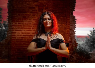 Một cô gái tóc nâu với mái tóc dài trong chiếc váy dạ hội trong một lâu đài Gothic cổ điển. Một người phụ nữ trông giống như một phù thủy độc ác hoặc phù thủy trong một nhà thờ cũ bị bỏ hoang. Người mẫu nữ tạo dáng trong Halloween