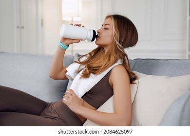Un modelo atractivo es beber agua después de hacer ejercicio por la mañana. Ella está sosteniendo una botella de agua en su mano derecha. Sus ojos están cerrados.