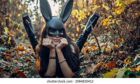Una chica con una máscara negra yace sobre las hojas.