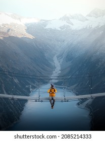 Mand i gul jakke sidder på en hængebro over en sø i Olpererhutte, Østrig