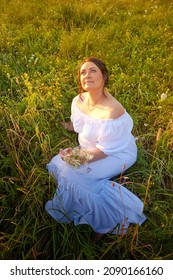 Countryside plump chubby pleasant woman in white dres in green grass field. Girl in an old Russian dress of a noblewoman posing outdoors on nature in a day or evening in Russia