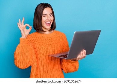 Chân dung của cô gái có kỹ năng vui vẻ hấp dẫn sử dụng máy tính xách tay cho thấy dấu hiệu đồng ý nháy mắt bị cô lập trên nền màu xanh sáng
