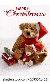 Christmas card with greetings and vintage style two teddy bears with red Santa cap sitting on white snow background