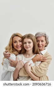 Família caucasiana de avó, mãe e neta se abraçando e olhando para a câmera. Conceito de idade e geração. Relacionamento familiar e proximidade. Fundo branco. Sessão de estúdio. Espaço para cópia