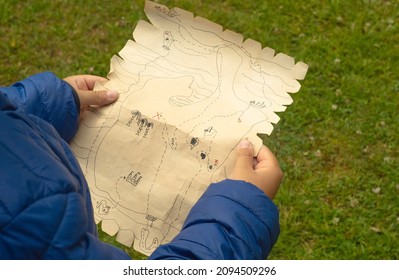 Un niño sostiene una vieja tarjeta pirata en sus manos. La búsqueda de los niños. Tesoros piratas. Juegos activos al aire libre.