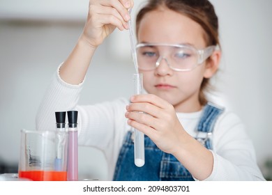 科学プロジェクトを行うことに焦点を当てた少女は、ピペットに液体を加え、底に白い塩の粉末を付けます。ゆっくりと正確に動こうとする。テーブルの後ろ。彼女の手に焦点を当てます。