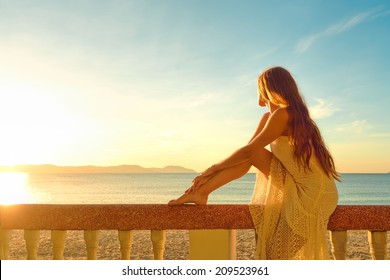 A woman on a balcony looking at the beautiful sunset