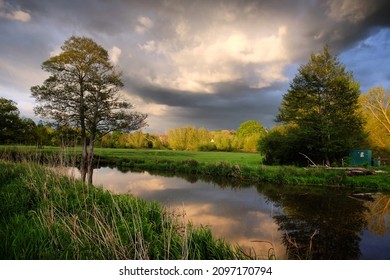 Stormachtige luchten en regen terwijl de zon ondergaat boven de rivier de Wey en weilanden in Godalming, Surrey, VK