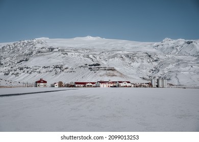 伝統的な農家とフィヨルドと山が雪に覆われたアイスランドの冬の風景。晴れた冬の日の青い空。