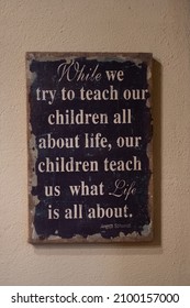 Teken op een muur met de tekst "Terwijl we proberen onze kinderen alles over het leven te leren, leren onze kinderen ons waar het in het leven om draait. Lessen van het leven. Citaat.