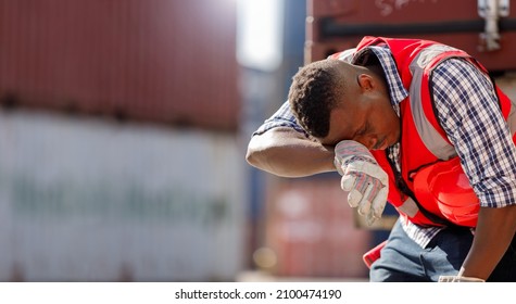 Los trabajadores afroamericanos están agotados por el trabajo duro. Un trabajador del patio de contenedores que lleva un chaleco reflectante rojo y un casco está de pie para secarse el sudor debido al clima cálido.