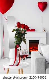 Vaas met mooie bloemen en glazen met wijn op tafel in de woonkamer ingericht voor Valentijnsdag