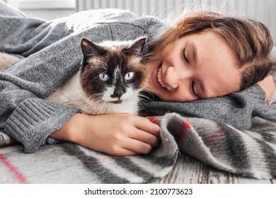 Jonge vrouw rust thuis in een warme gebreide trui met een kat