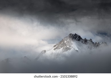 Berggipfel in Wolken mit einem Sonnenstrahl, der den Gipfel beleuchtet, Landschaft der Schweizer Alpen