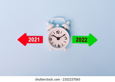 2021 and 2022, symbolize the change from 2021 to the new year 2022. Minimalist composition of white clock and Red arrow and green arrow showing towards the years 2021 and 2022 on white background