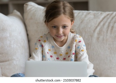 Addicted to modern tech adorable happy preteen kid girl looking at laptop screen, feeling excited watching funny cartoons online or video in social network, playing games or communicating distantly.