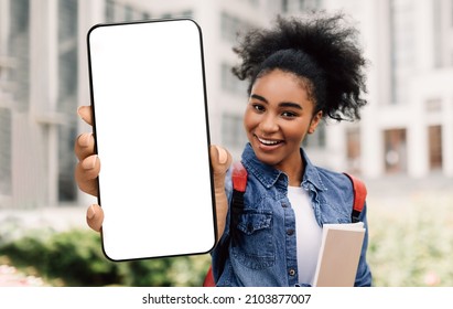 Estudiante negra feliz mostrando un gran teléfono inteligente en blanco a la cámara mientras está de pie cerca del edificio de la universidad, mujer afroamericana recomendando una aplicación para estudiar y educación en línea, collage, maqueta