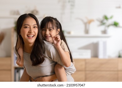 家で一緒に遊んでいる彼女の娘を保持している幸せなアジアのお母さん