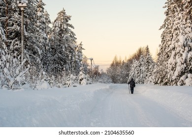El hombre camina por un camino rural, despejado de nieve, pasando por un bosque cubierto de nieve. Maravilloso paisaje de campo de invierno.