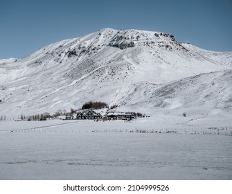 伝統的な農家とフィヨルドと山が雪に覆われたアイスランドの冬の風景。晴れた冬の日の青い空。