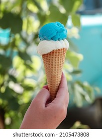 Hand holding waffle cone with two ice cream balls on the street Refreshing snack on a hot day Vertical photo