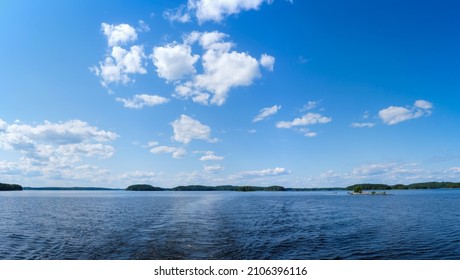 Vista trasera de un barco a motor navegando en aguas tranquilas, con vistas a las islas y al cielo azul. Lago Saimaa, Finlandia.