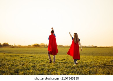 穿着超级英雄服装的快乐男人和女人，强大成功的超级英雄飞去救援，在大自然中迎着夕阳，男人和女人在田野上奔跑