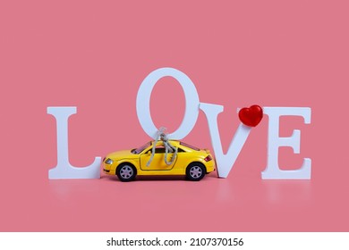 Yellow car carries the word Love on a pink background. Valentine's Day.