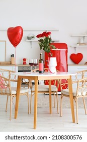 Flasche Wein, Gläser und Vase mit Rosen auf dem Esstisch in der zum Valentinstag dekorierten Küche