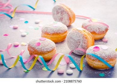 Traditionele Berliner voor carnaval en feest. Duitse Krapfen of donuts met slingers en confetti. Kleurrijke carnavals- of verjaardagsafbeelding.