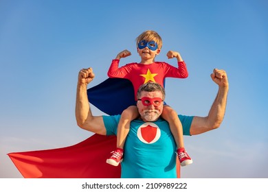Pria senior superhero dan anak bermain di luar ruangan. Kakek pahlawan super dan anak laki-laki bersenang-senang bersama dengan latar belakang langit biru musim panas. Konsep liburan keluarga. Selamat Hari Ayah