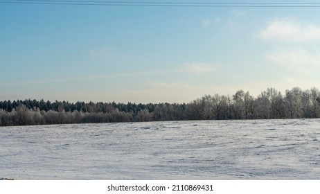 背景の木と雪の下で冬の農地風景風景。雪に覆われた田舎の冬の風景。テキスト用のスペース。